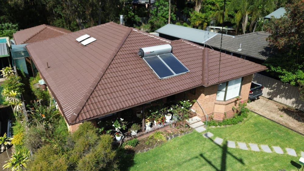 An Aerial View of a House With Two Solar Panels on the Roof — Roof Restoration Masters In Boolaroo, NSW
