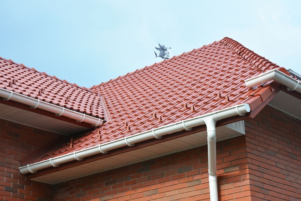 A Brick House With a Red Tiled Roof and White Gutters — Roof Restoration Masters In Belmont, NSW