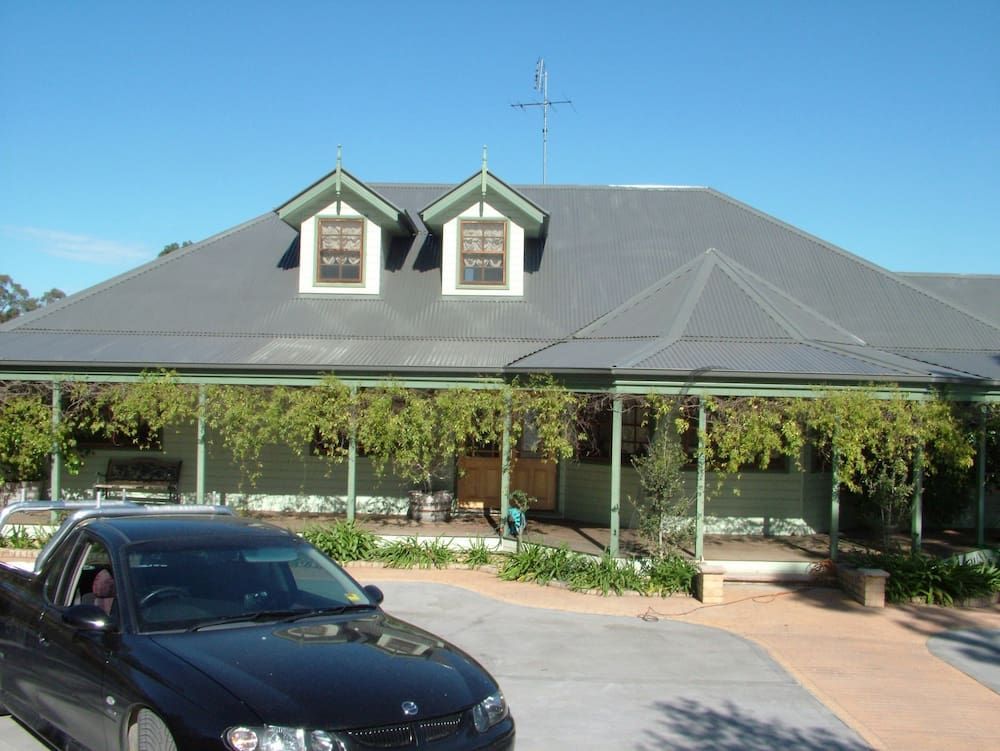 A Black Car is Parked in Front of a Large House — Roof Restoration Masters In Jewells, NSW