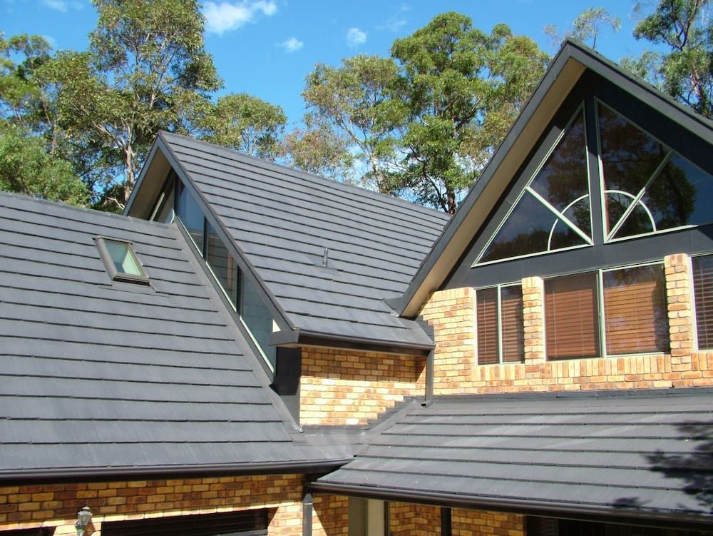 A Brick House With a Roof That Has a Skylight on It — Roof Restoration Masters In Ashtonfield, NSW