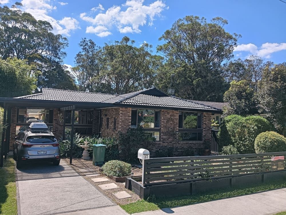 A Car is Parked in Front of a House on a Sunny Day — Roof Restoration Masters In Narara, NSW