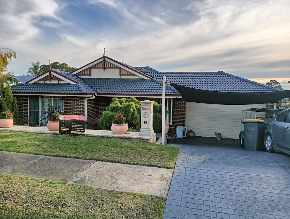 A Large House With a Car Parked in Front of It — Roof Restoration Masters In Elermore Vale, NSW