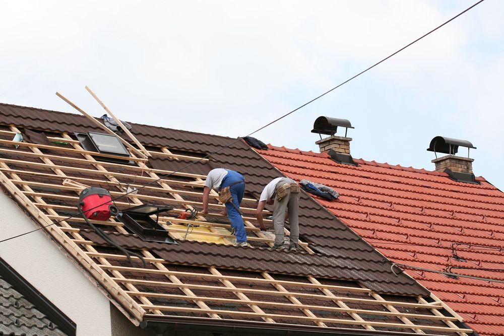 Two Men Are Working on the Roof of a House — Roof Restoration Masters In Mannering Park, NSW