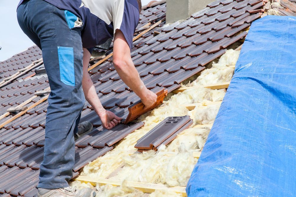 A Man is Working on the Roof of a House — Roof Restoration Masters In Valentine, NSW
