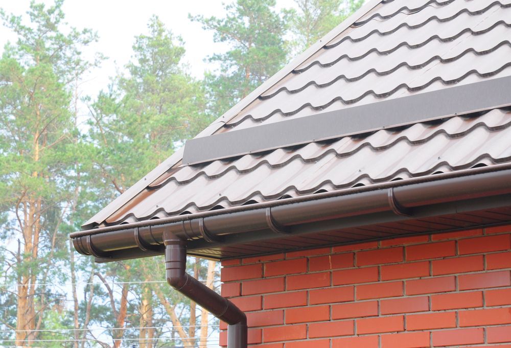 A Close Up of a Gutter on the Side of a Brick House — Roof Restoration Masters In Gosford, NSW