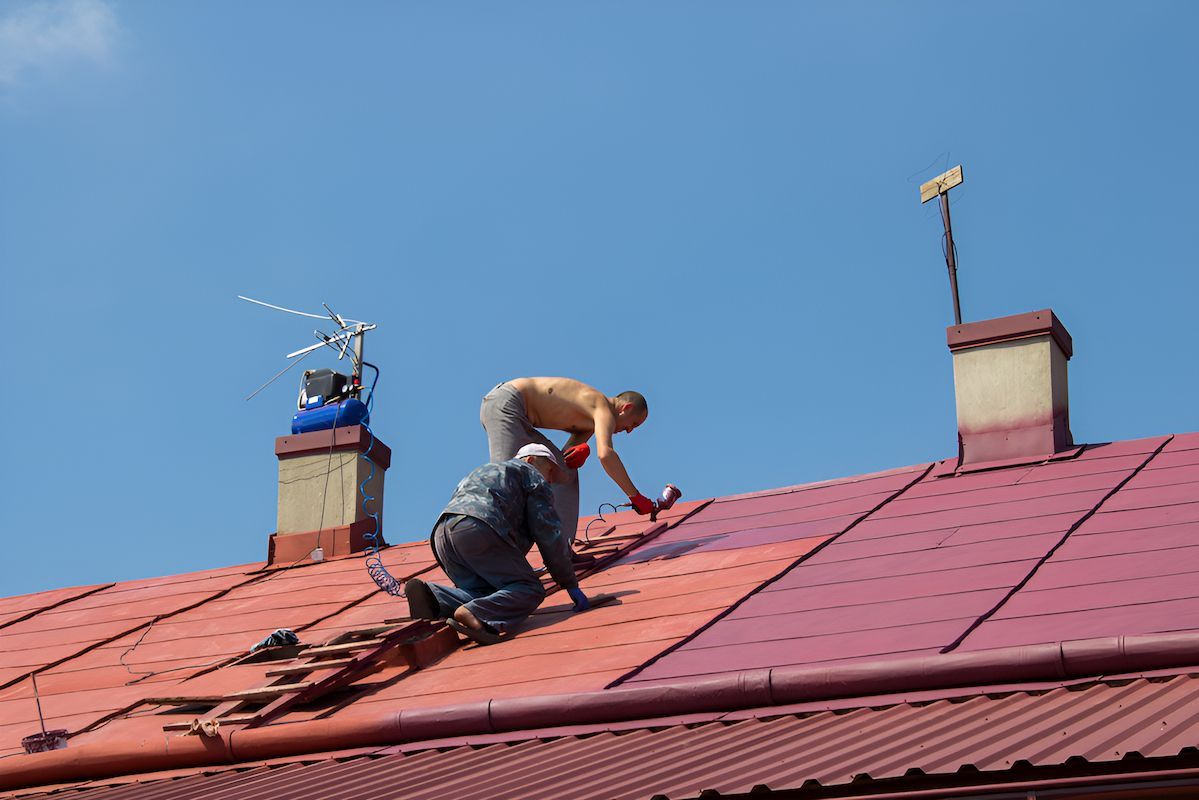 Two Men Are Working on the Roof of a Building — Roof Restoration Masters In Cooranbong, NSW