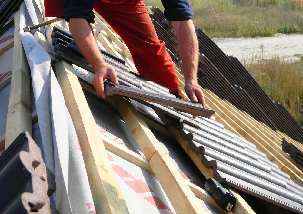 A Man is Working on the Roof of a House — Roof Restoration Masters In Bonnells Bay, NSW