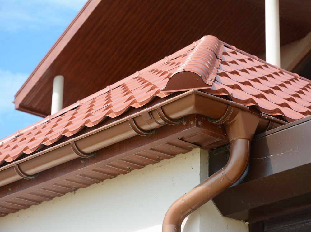 A Brown Gutter on the Side of a House With a Red Tile Roof — Roof Restoration Masters In Cooranbong, NSW