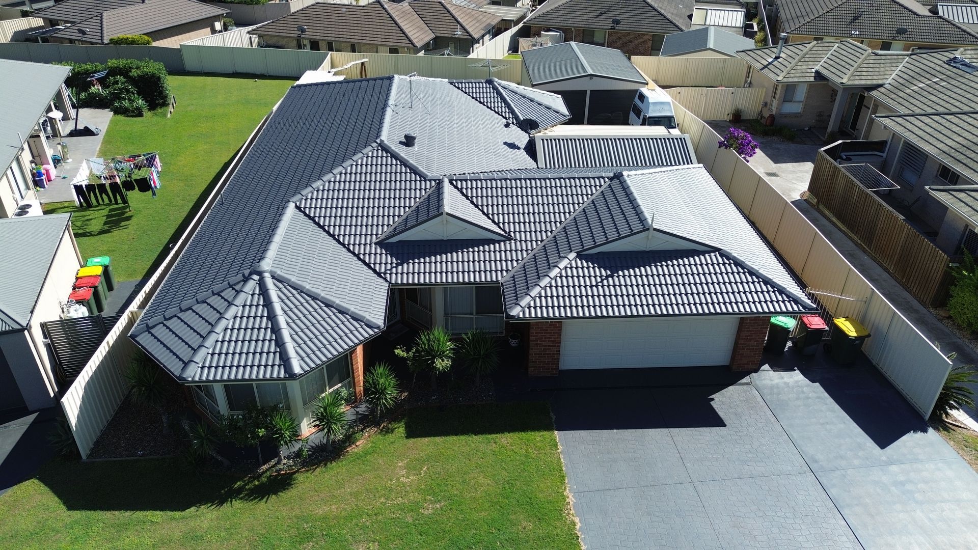 Red Tiled Roof With A Skylight And A Blue Sky In The Background — Roof Restoration Masters in Morisset, NSW