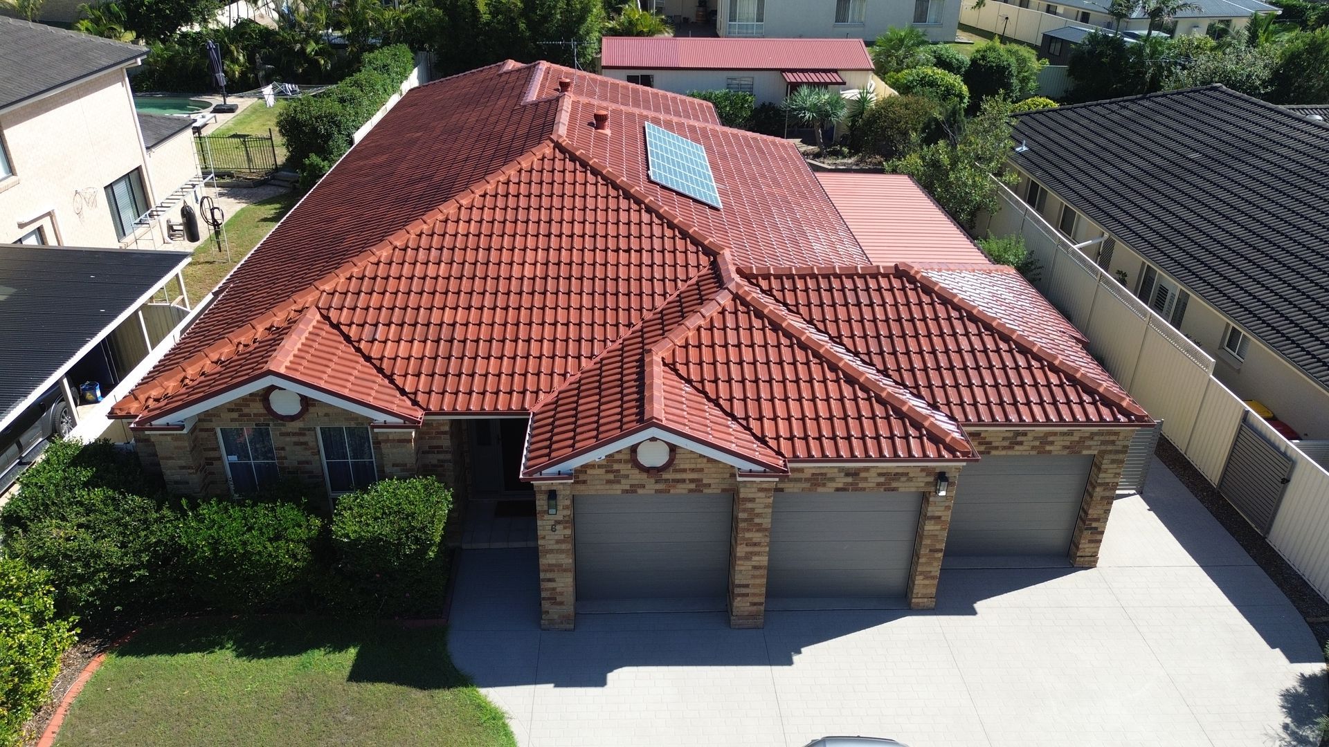 Red Tiled Roof With A Skylight And A Blue Sky In The Background — Roof Restoration Masters in Morisset, NSW