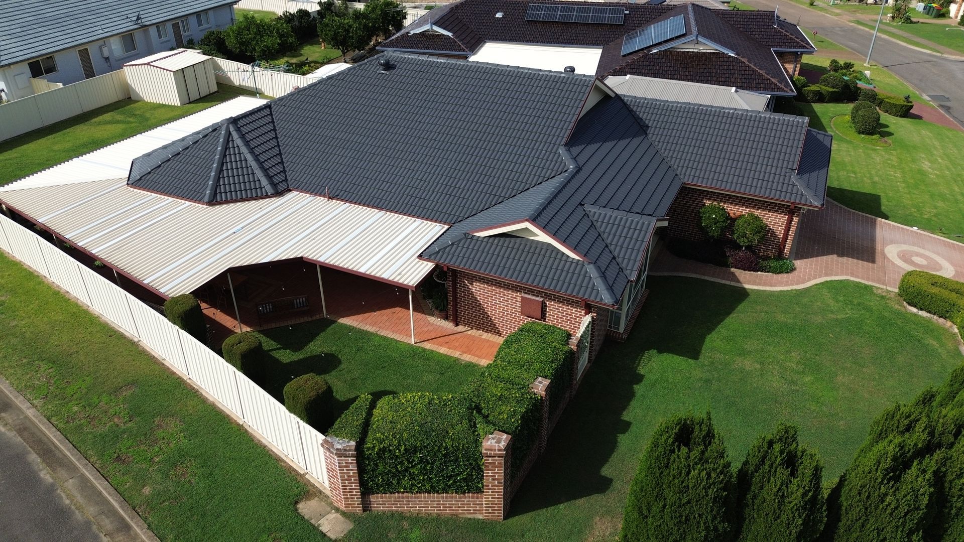 Red Tiled Roof With A Skylight And A Blue Sky In The Background — Roof Restoration Masters in Morisset, NSW
