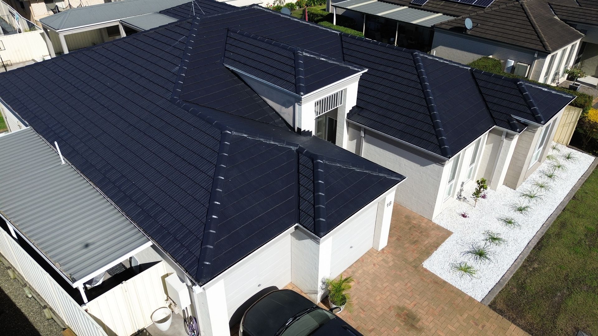 Red Tiled Roof With A Skylight And A Blue Sky In The Background — Roof Restoration Masters in Morisset, NSW