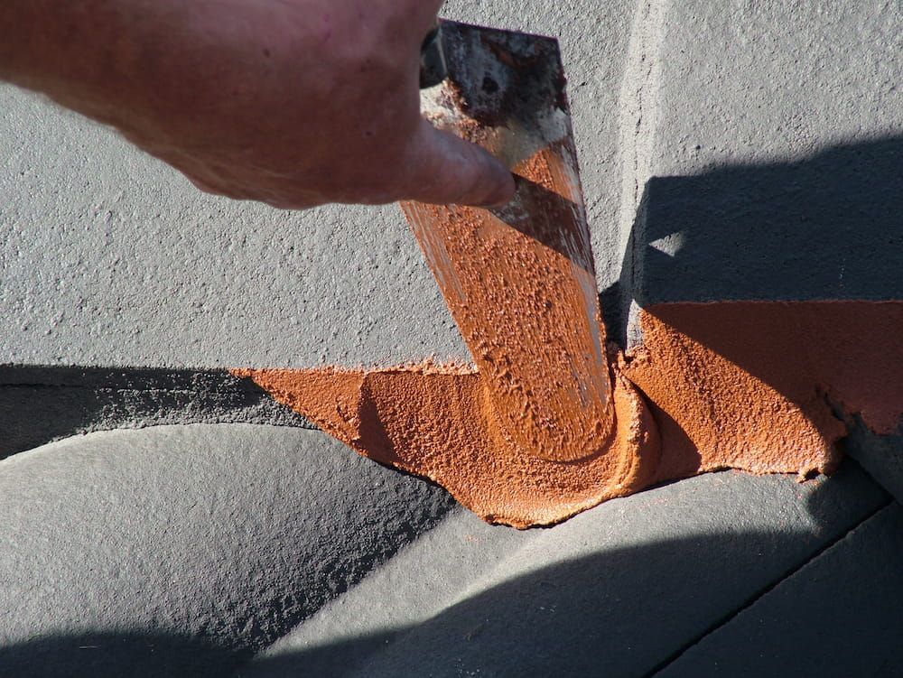 A Person Applying Sealant on the Roof With a Spatula — Roof Restoration Masters In Morisset Park, NSW