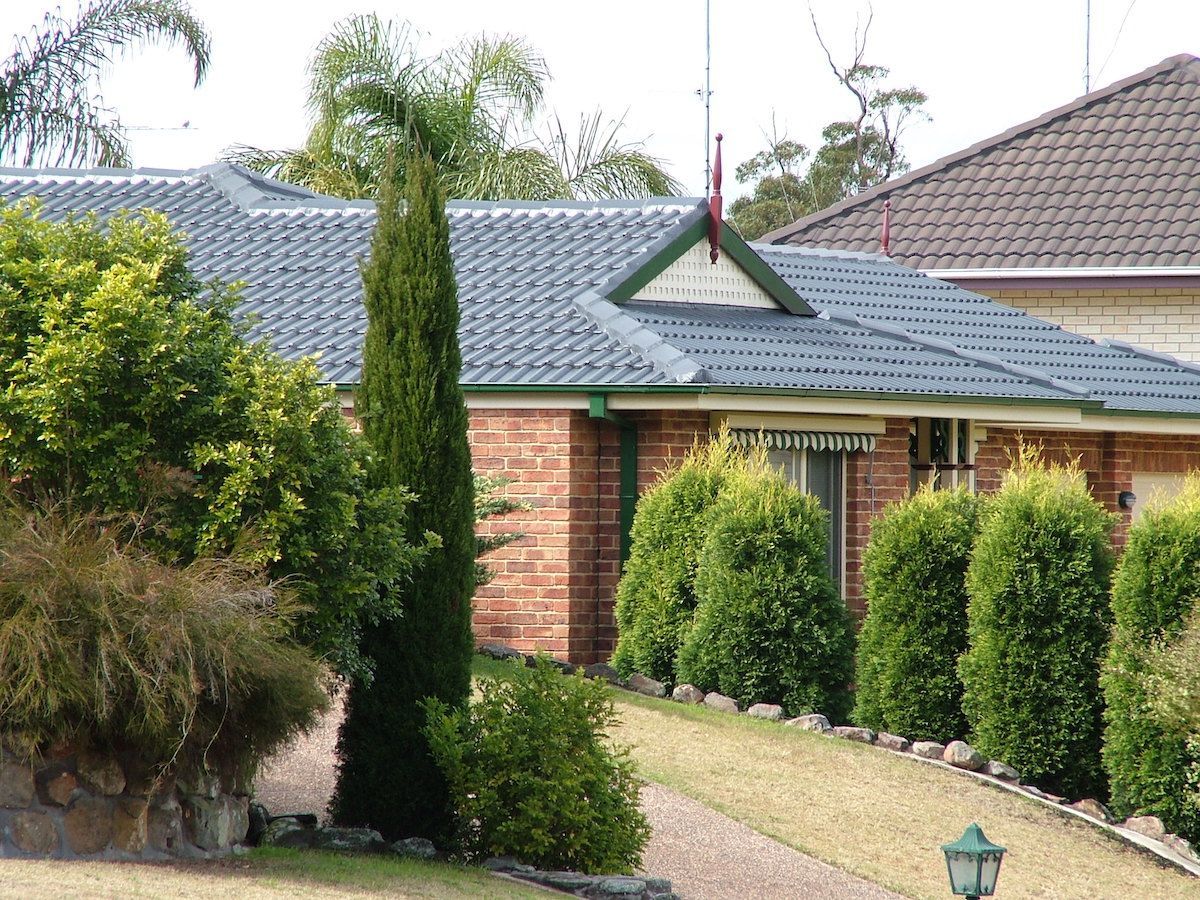Red Tiled Roof With A Skylight And A Blue Sky In The Background — Roof Restoration Masters in Morisset, NSW