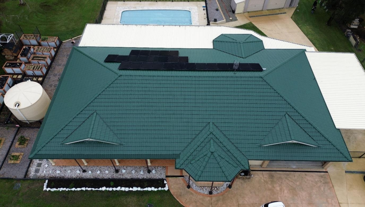Red Tiled Roof With A Skylight And A Blue Sky In The Background — Roof Restoration Masters in Morisset, NSW