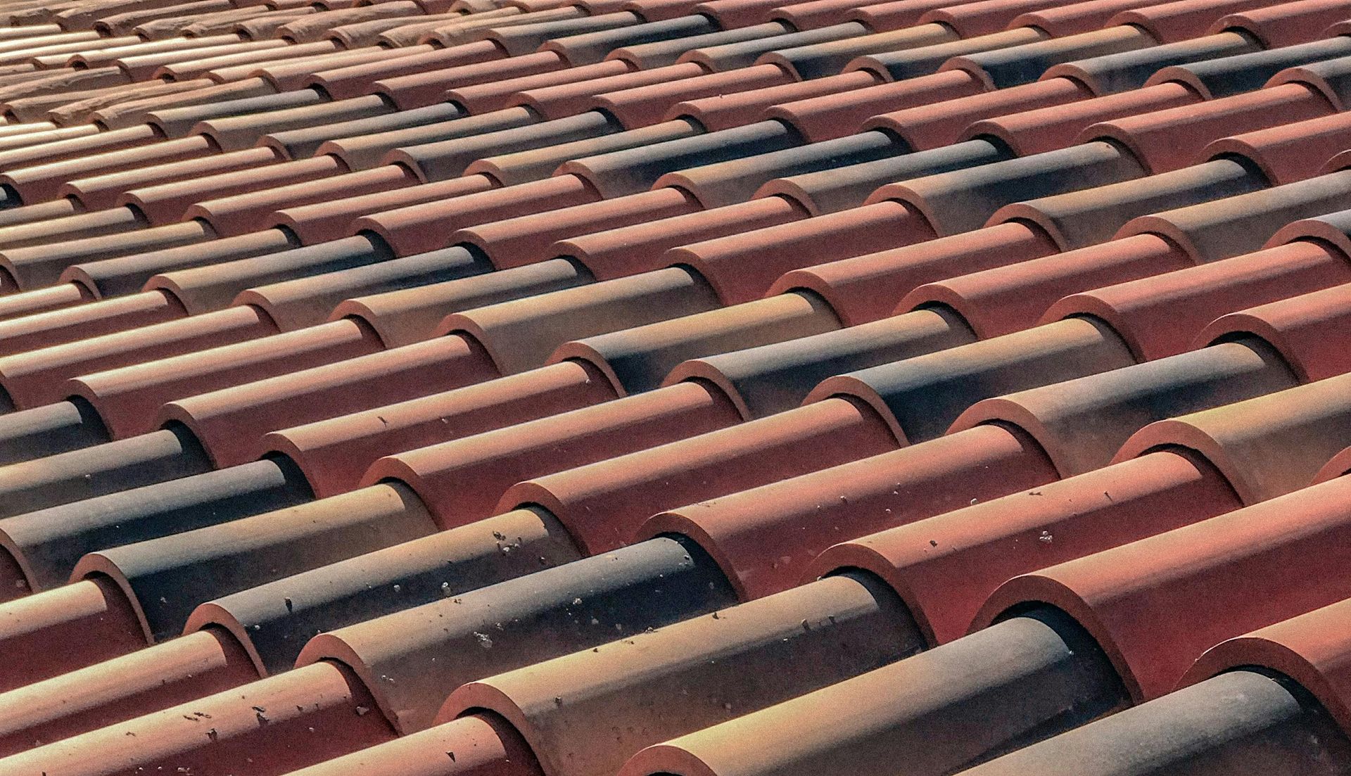 A close up of a row of red and black tiles on a roof — Roof Restoration Masters In Central Coast, NSW