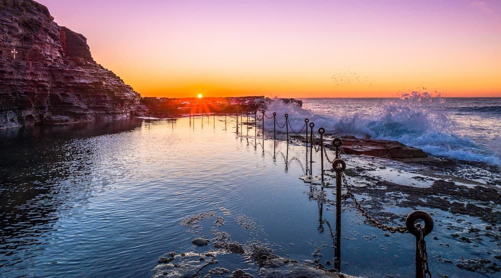 A Sunset Over a Body of Water With Waves Crashing on the Shore — Roof Restoration Masters In New Lambton, NSW