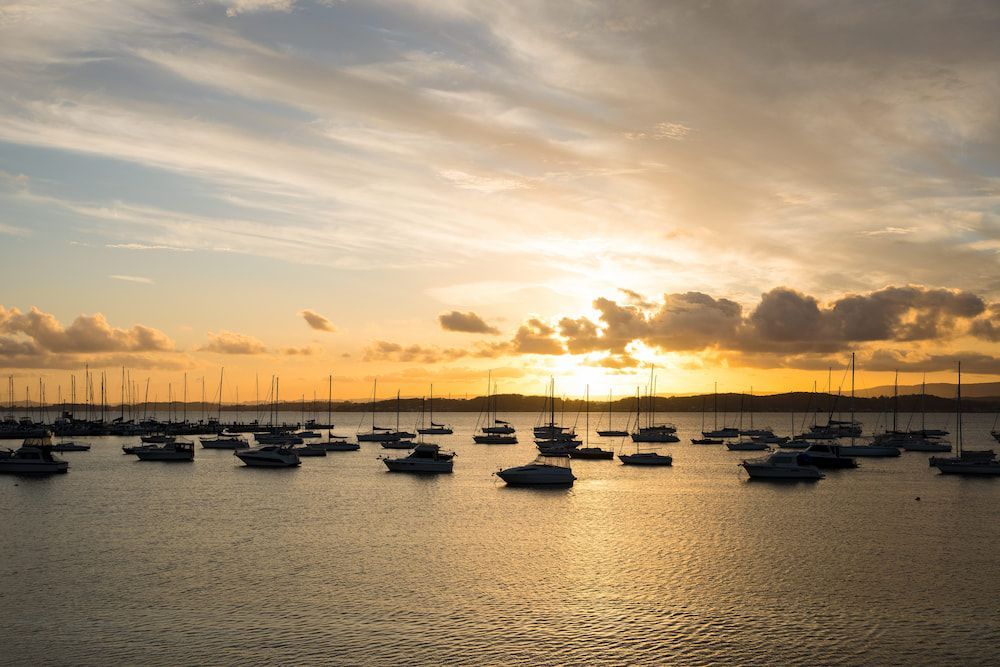 There Are Many Boats in the Water at Sunset — Roof Restoration Masters In Lake Macquarie, NSW