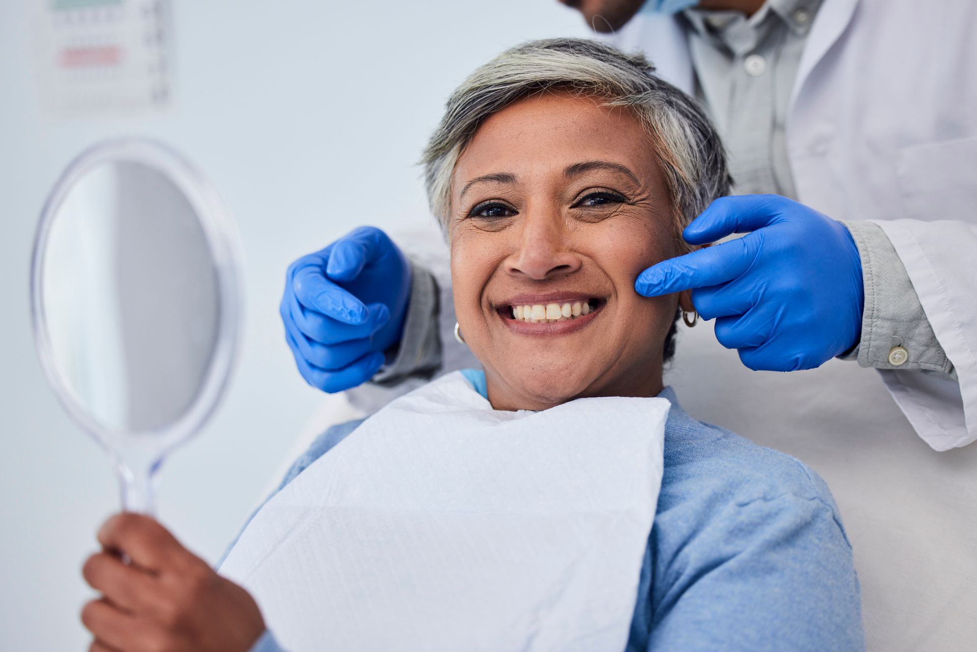 Cosmetic dentist showing patient smile results in dental office.