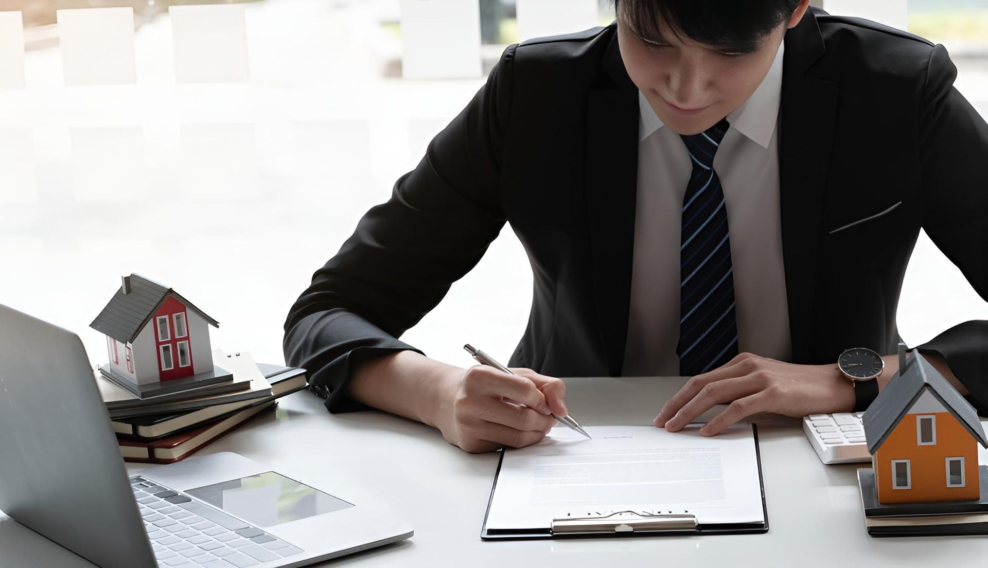 A Man In A Suit And Tie Is Sitting At A Desk — Angel Conveyancing In Larrakeyah, NT