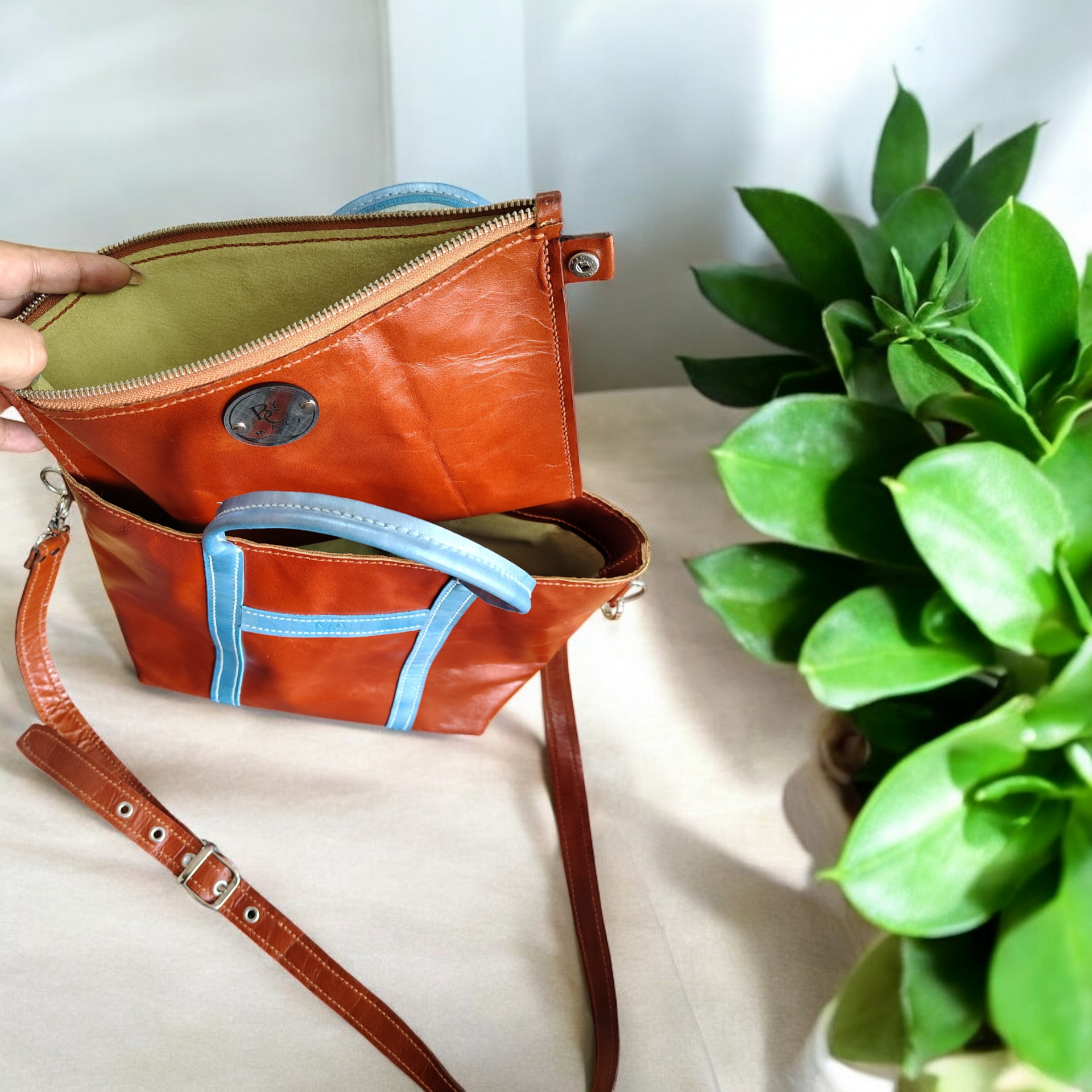 Bolso tote de piel marrón con ribete azul, sobre superficie de madera.