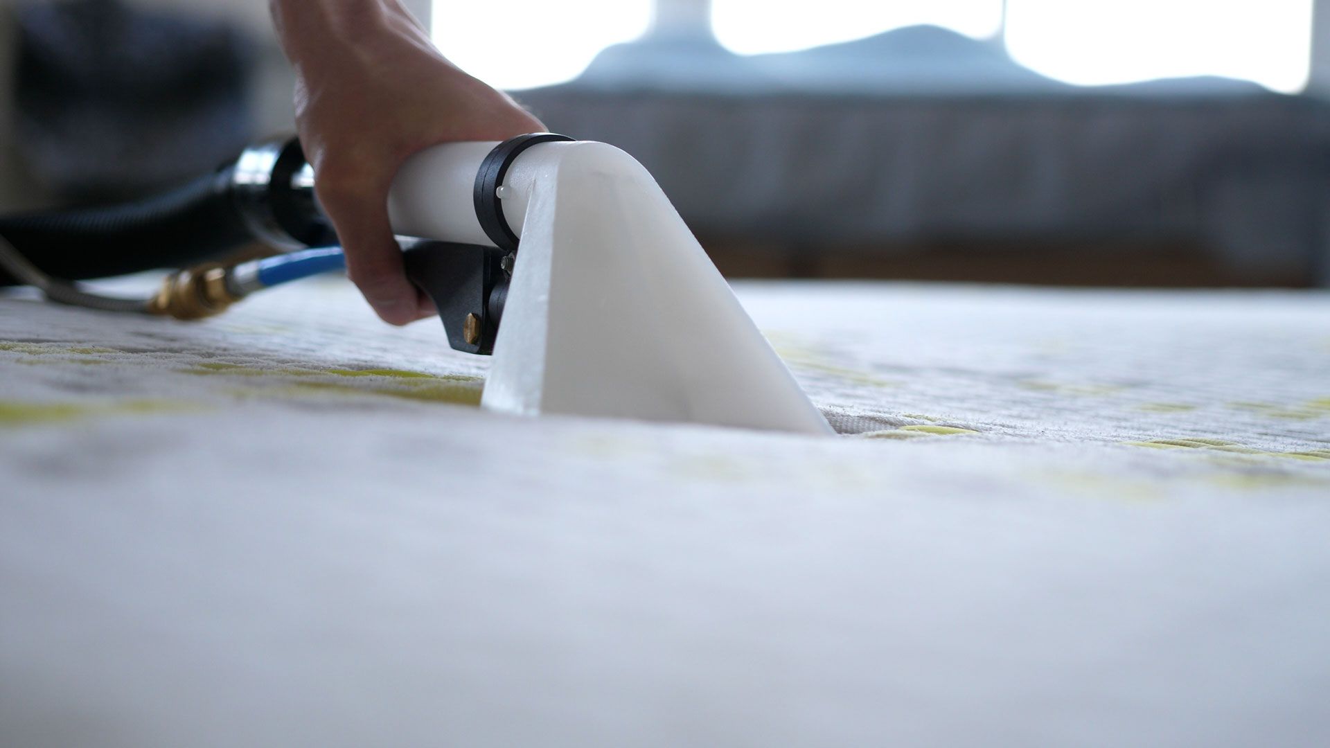 A person is cleaning a carpet with a vacuum cleaner.