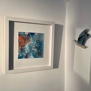 An image of a framed  blue and orange coloured mixed mediamedia artwork