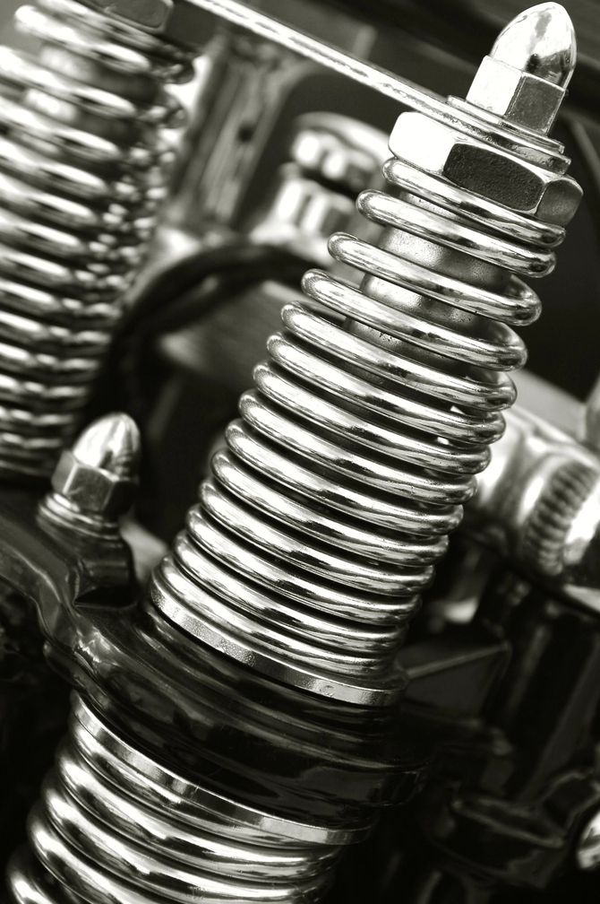 Primo piano di molle e bulloni metallici avvolti e lucenti in un assemblaggio meccanico.