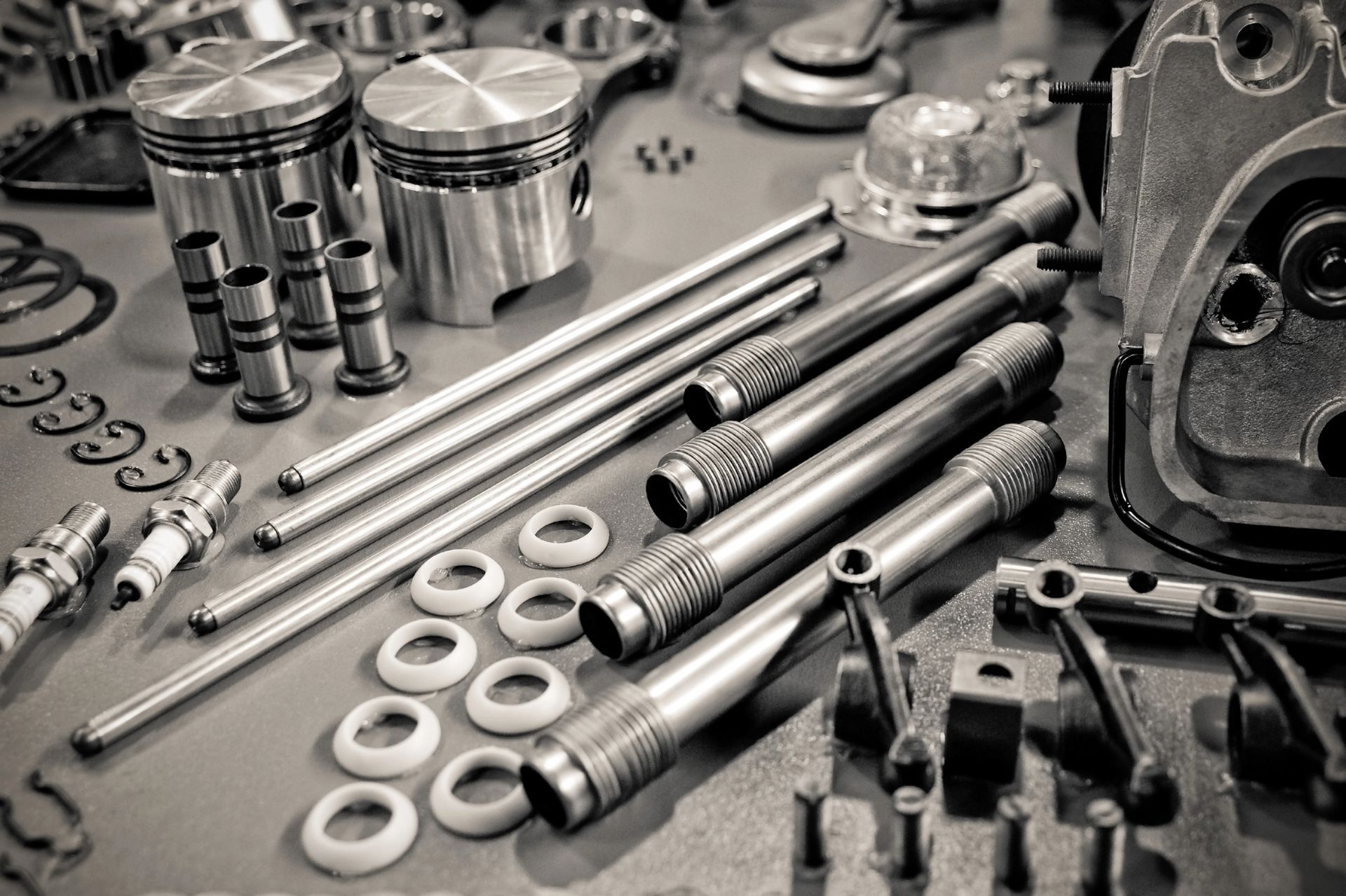 Vari componenti metallici del motore e bulloni disposti su un tavolo da officina.
