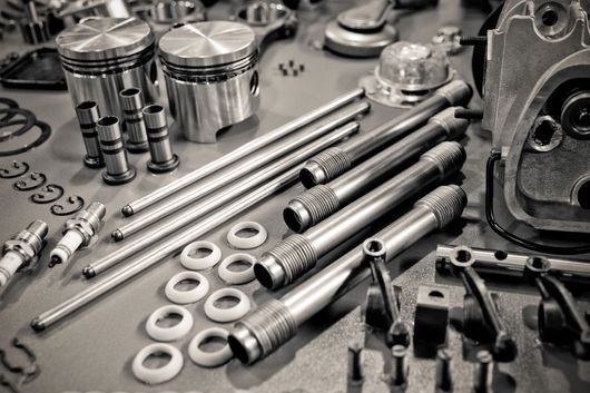 Vari componenti metallici di motori e attrezzi disposti su un banco da lavoro in un'officina.