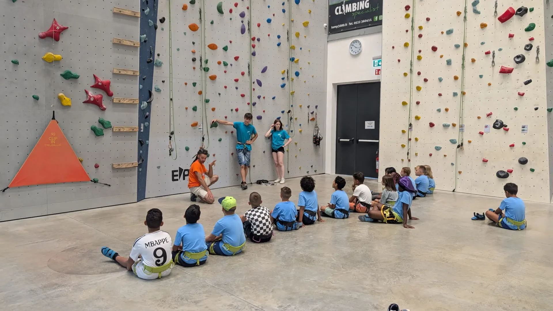 bambini e bambine in procinto di arrampicarsi nella palestra di arrampicata