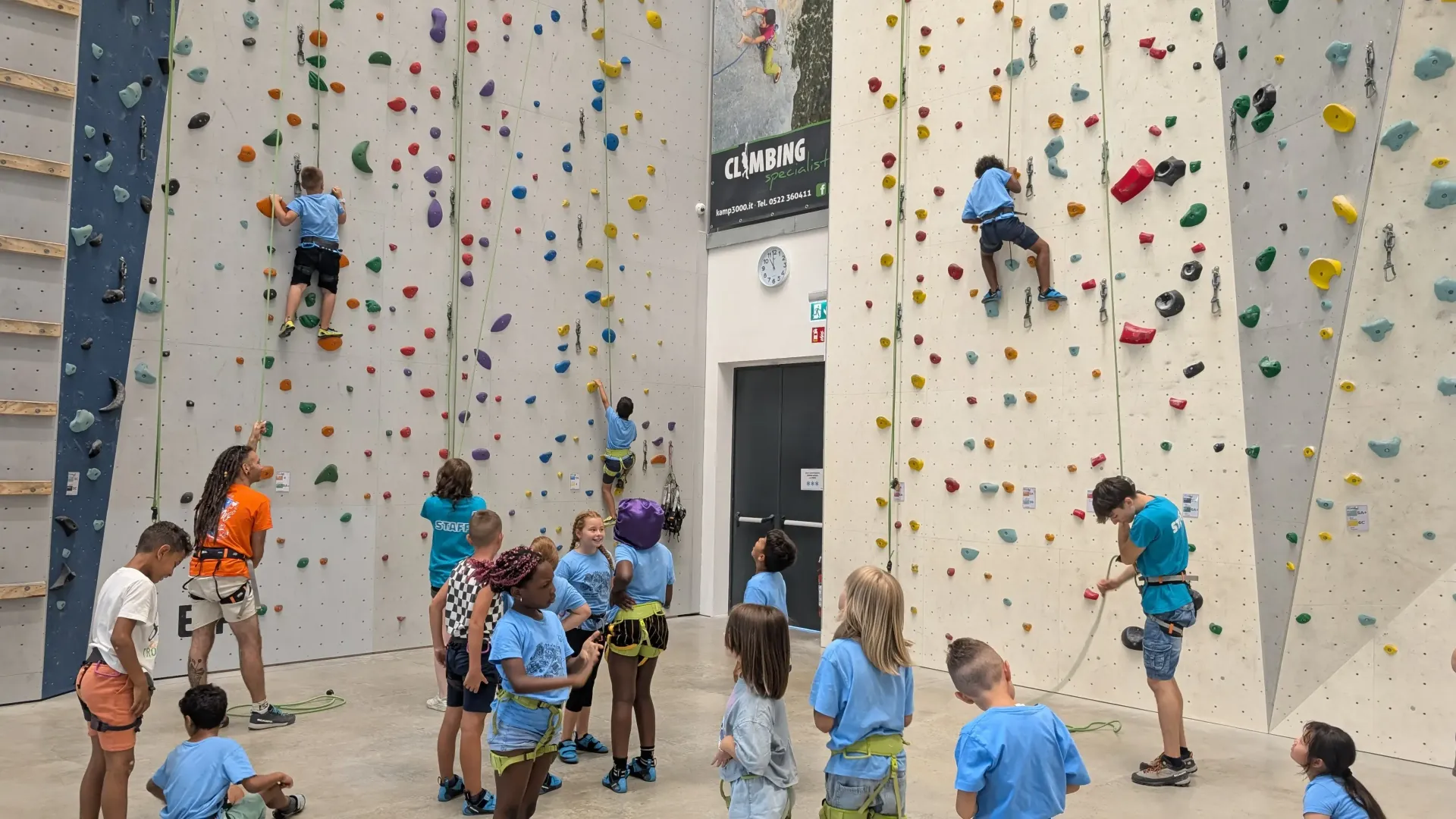 bambini e bambine in procinto di arrampicarsi nella palestra di arrampicata