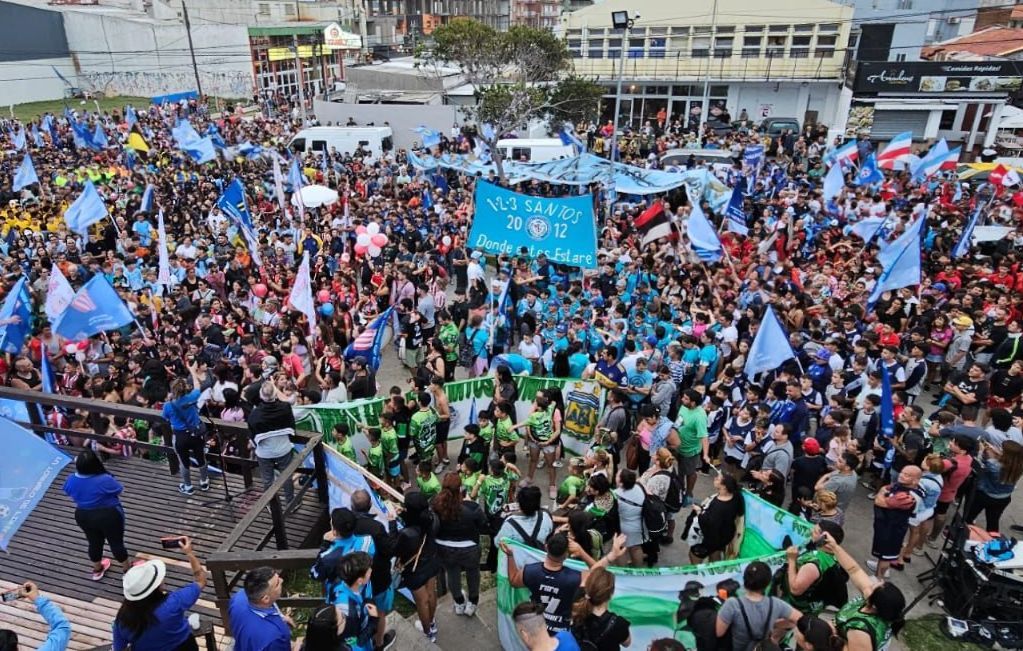 Una gran multitud, muchos con banderas, se reunió frente a un edificio. Predominaban las banderas azules, verdes y blancas.