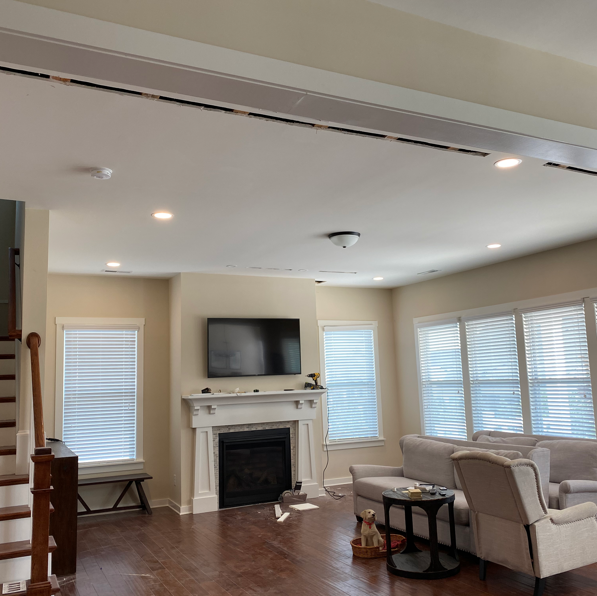 Living room with fireplace, TV, windows with blinds, sofa, and staircase.