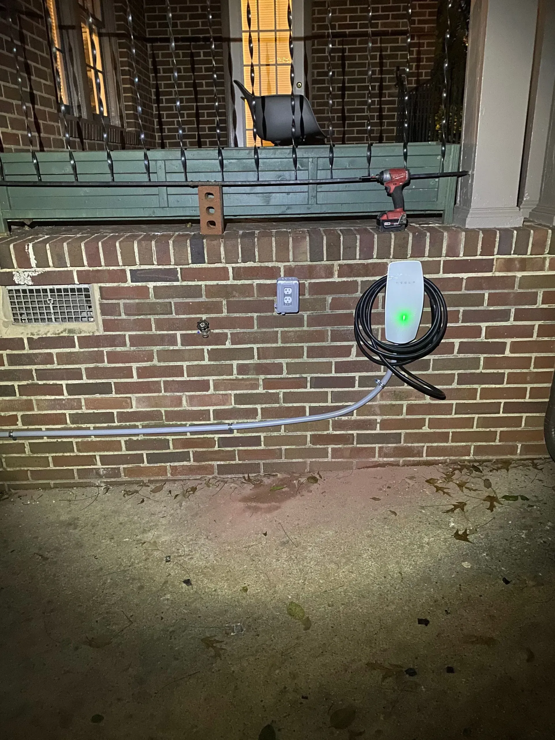 Electric vehicle charger mounted on a brick wall, with a coiled cable.