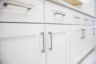 White cabinets with silver handles along a countertop.