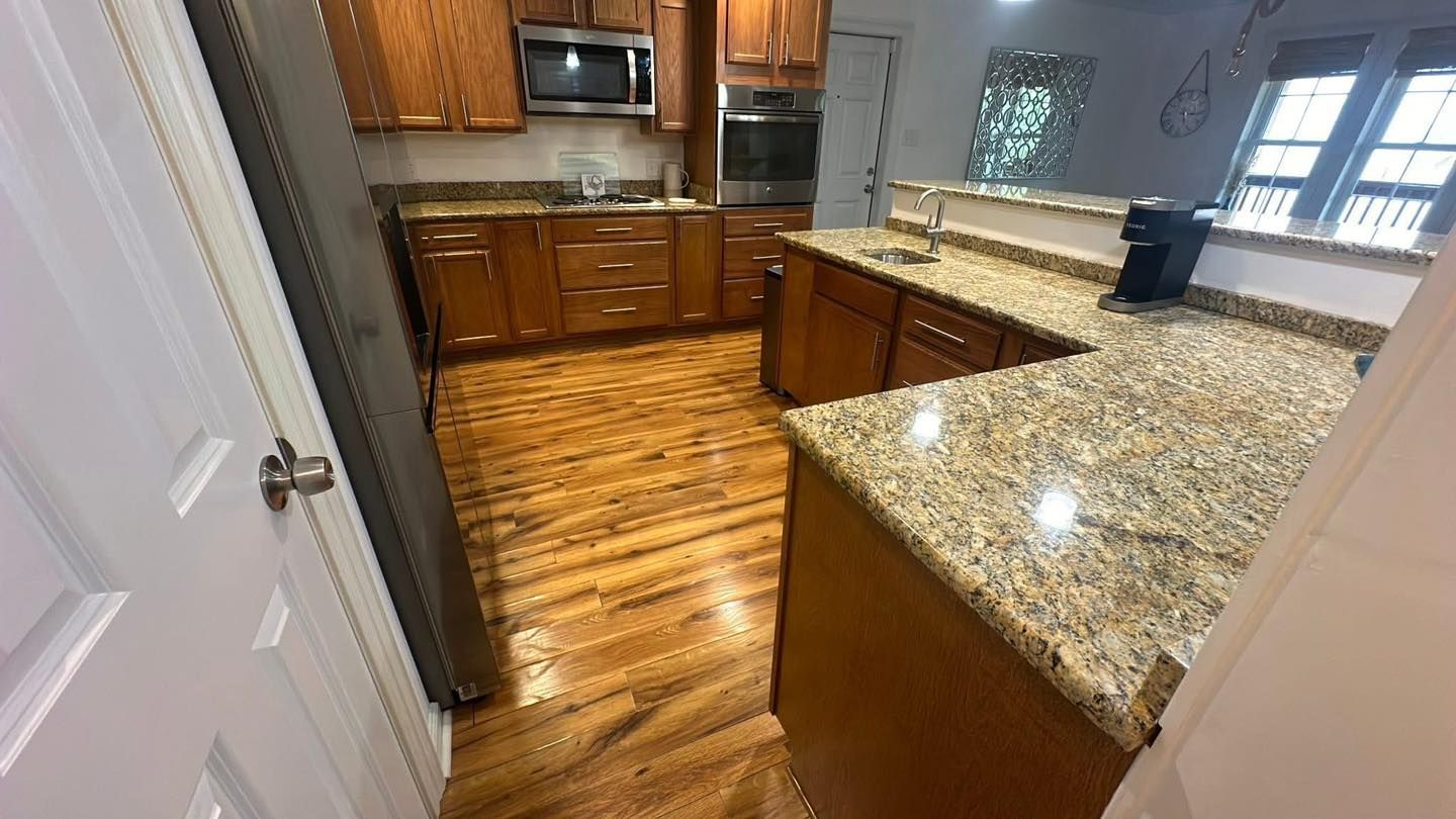 A kitchen featuring wooden cabinets, granite countertops, hardwood floors, and stainless steel appliances.