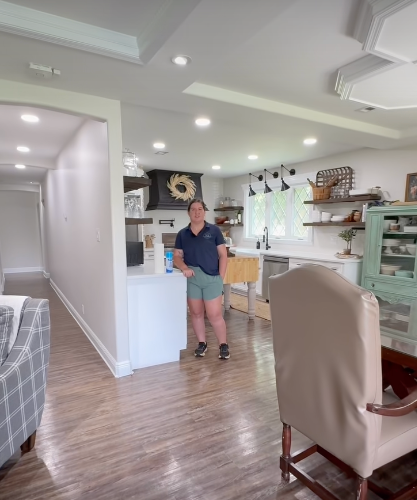 Bright kitchen with a person standing near the counter and dining chairs in the foreground