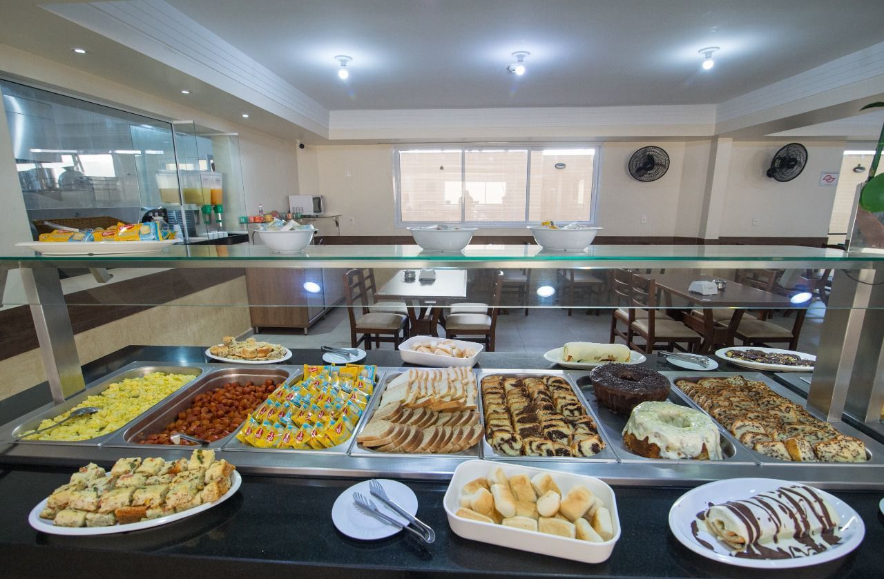 Buffet com diversos itens gastronômicos: panquecas, doces e outras sobremesas. Ambiente de restaurante.