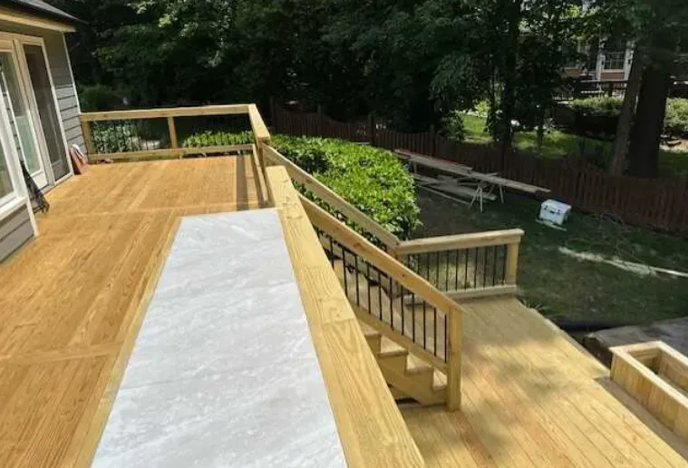 A wooden deck with stairs leading up to it in a backyard.