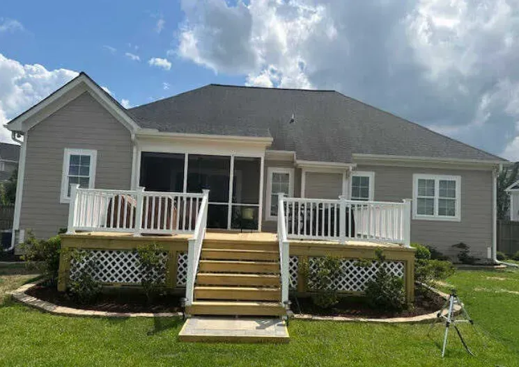 The back of a house with a screened in porch and a deck.