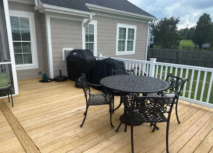 There is a table and chairs on the deck of a house.