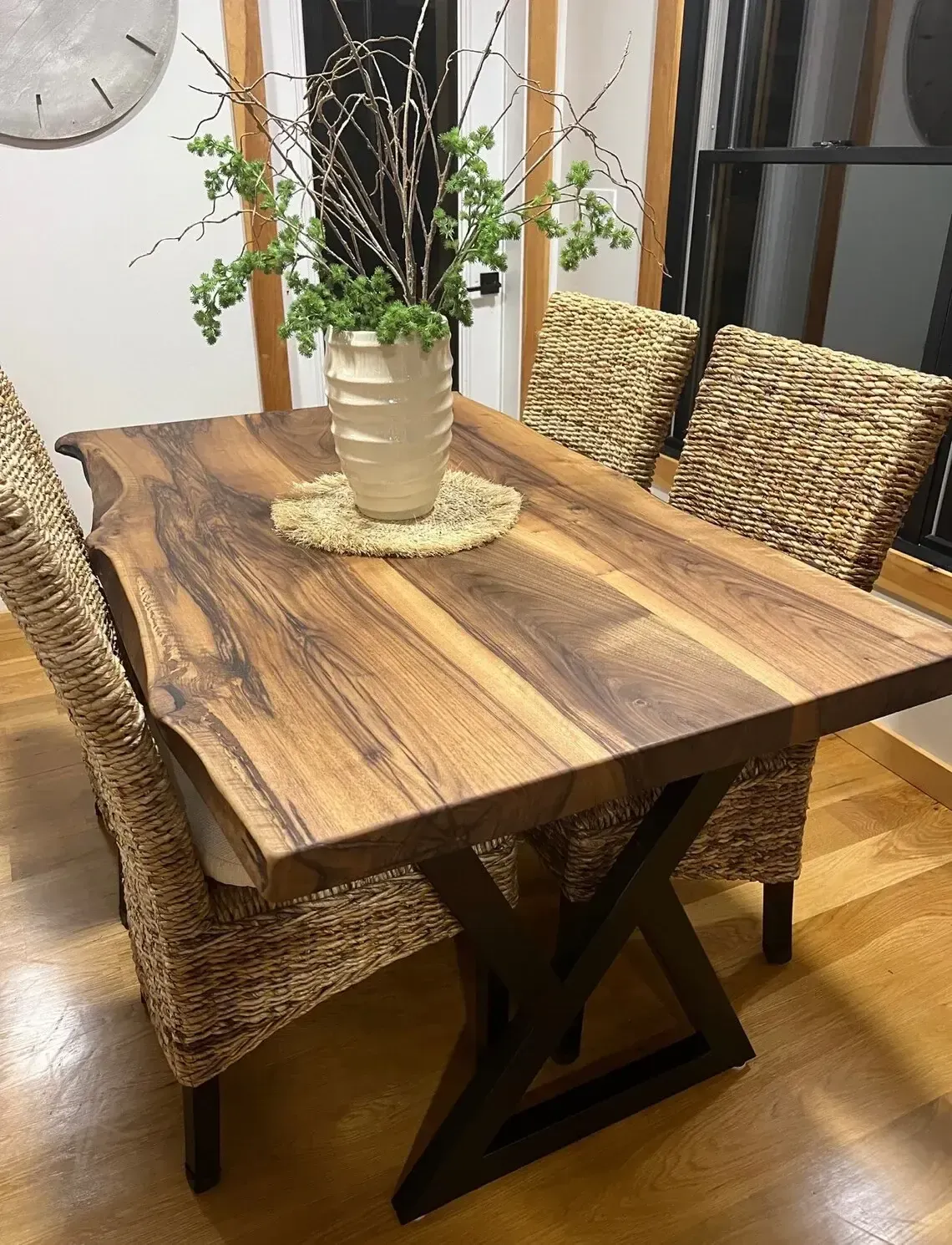 A wooden table with wicker chairs and a vase of flowers on it