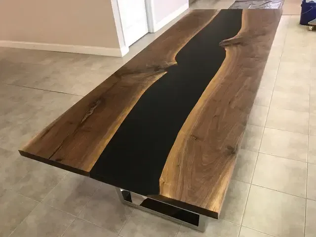 A wooden table with a black river in the middle is sitting on a tiled floor.