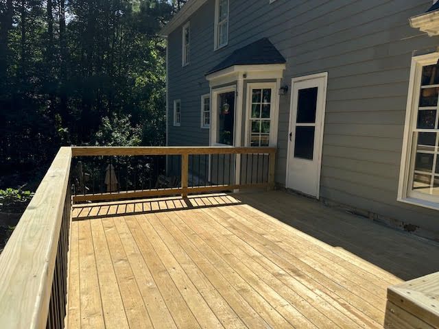 A large wooden deck is in front of a house.