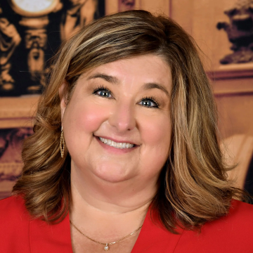Smiling woman in a red top against a warm indoor background