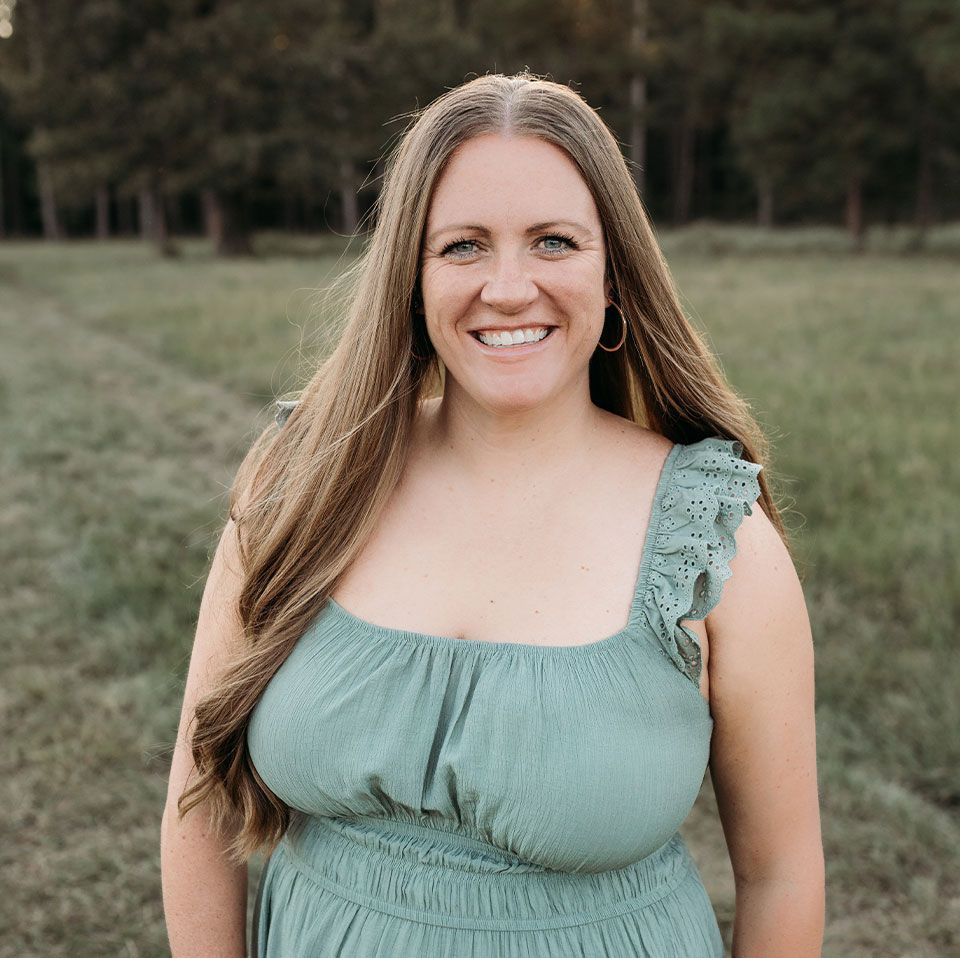 Smiling woman in a green dress standing in a grassy field