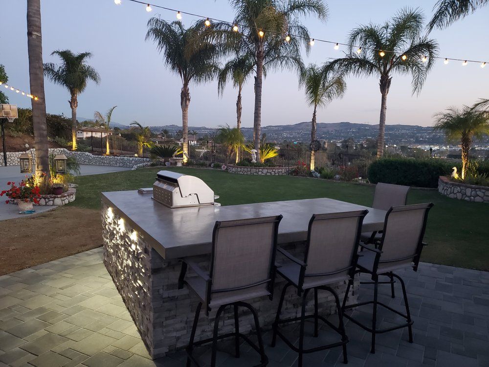 A patio with a table and chairs and palm trees in the background