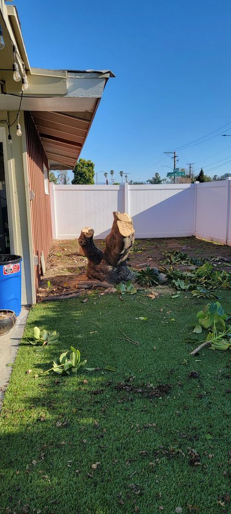 A tree stump is sitting in the grass in front of a house.