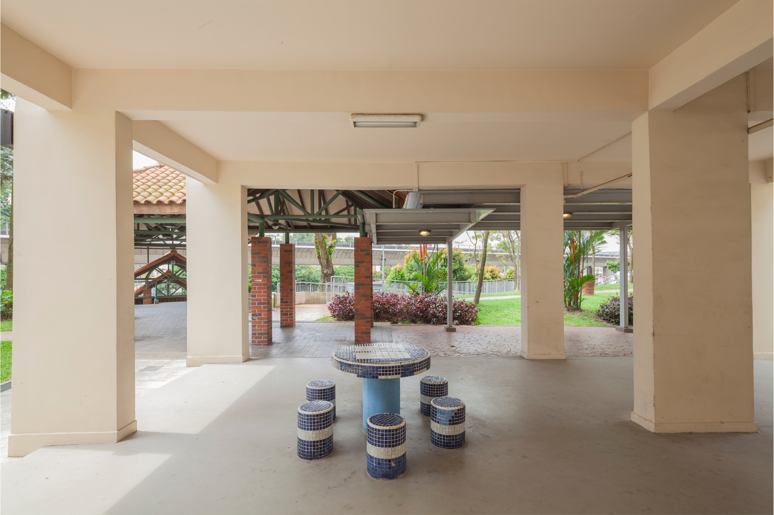 Covered patio with a table and stools; garden visible in the background.